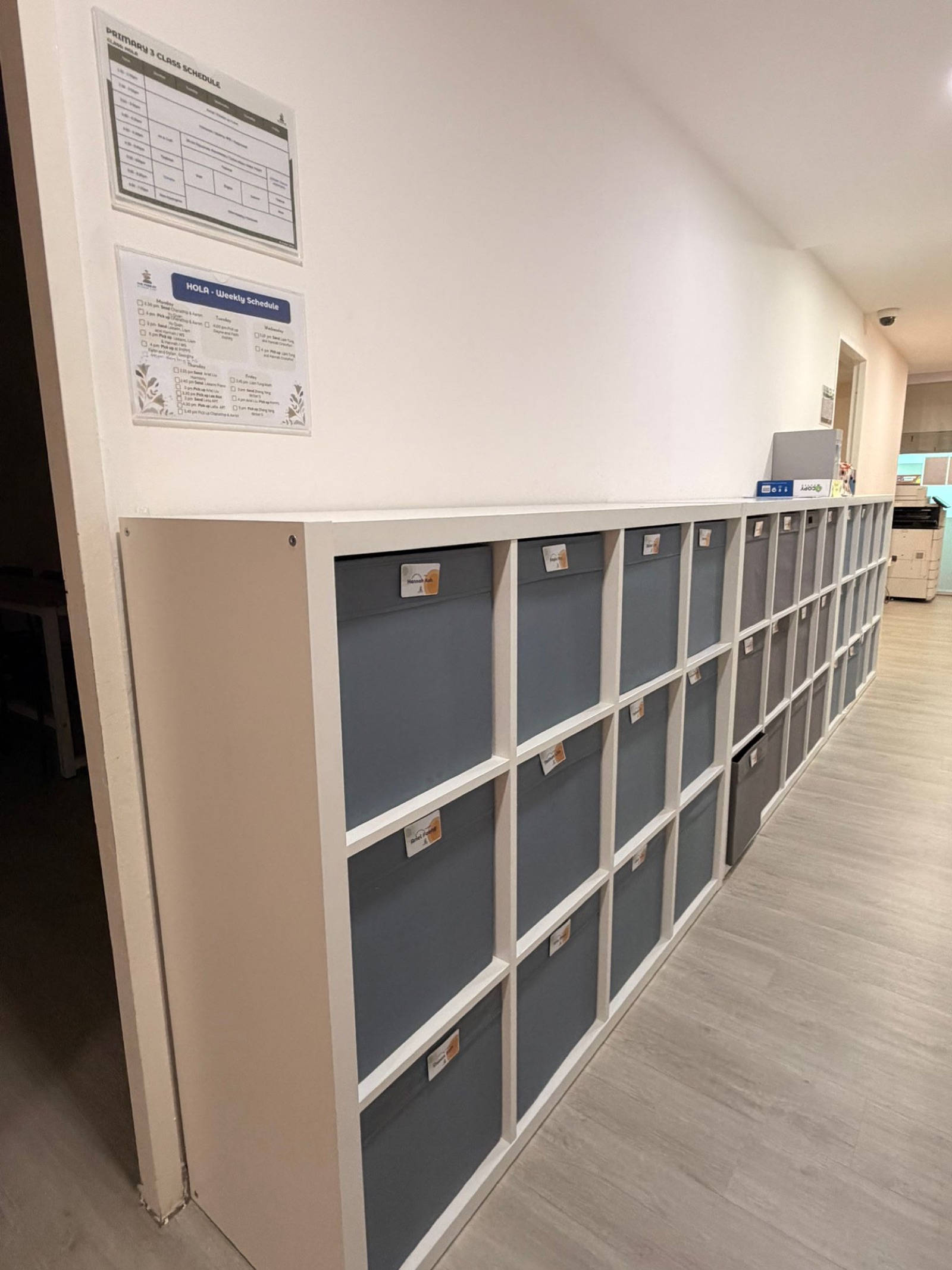 Student cubbies with weekly schedule and HOLA timetable on the wall