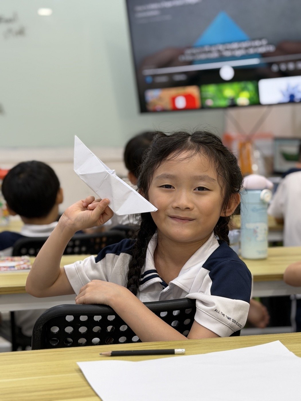 A Pebbles student smiling with a paper plane during enrichment time